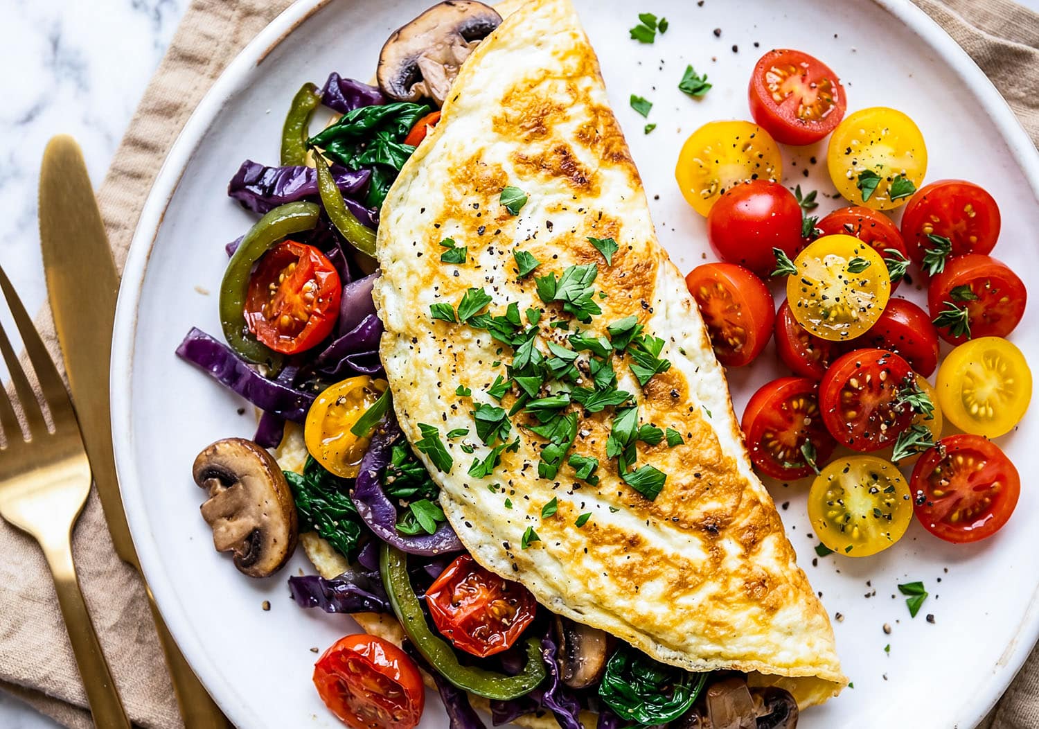 Veggie stuffed egg white omelet with spinach, peppers, mushrooms, and tomatoes on a white plate
beautifuleatsandthings.com