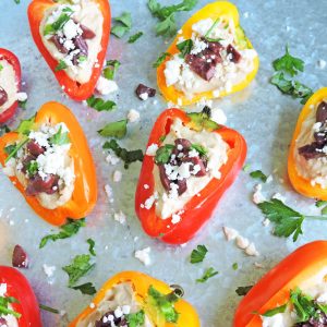 Mediterranean Hummus Stuffed Peppers-mini yellow, red, and orange bell peppers sliced in half and stuffed with hummus, topped with chopped Kalamata olives, feta, and parsley