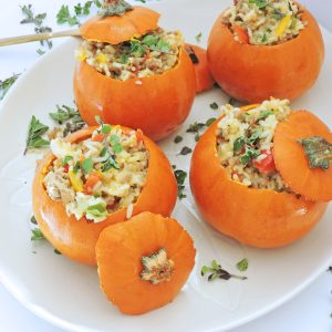 Mini Sausage & Rice Stuffed Pumpkins served on a white plate with thyme on top, the perfect Fall recipe for Thanksgiving