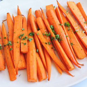 Ginger Maple Mustard & Herb Roasted Carrots with parsley on top made with Colman's Mustard on a white plate