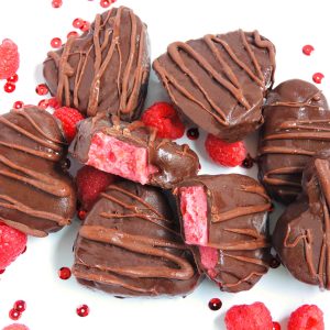 4-Ingredient Dark Chocolate Raspberry Hearts + Made with No Added Sugar, dark chocolate hearts with a pink raspberry and date filling, decorated with red Valentine's Day hearts