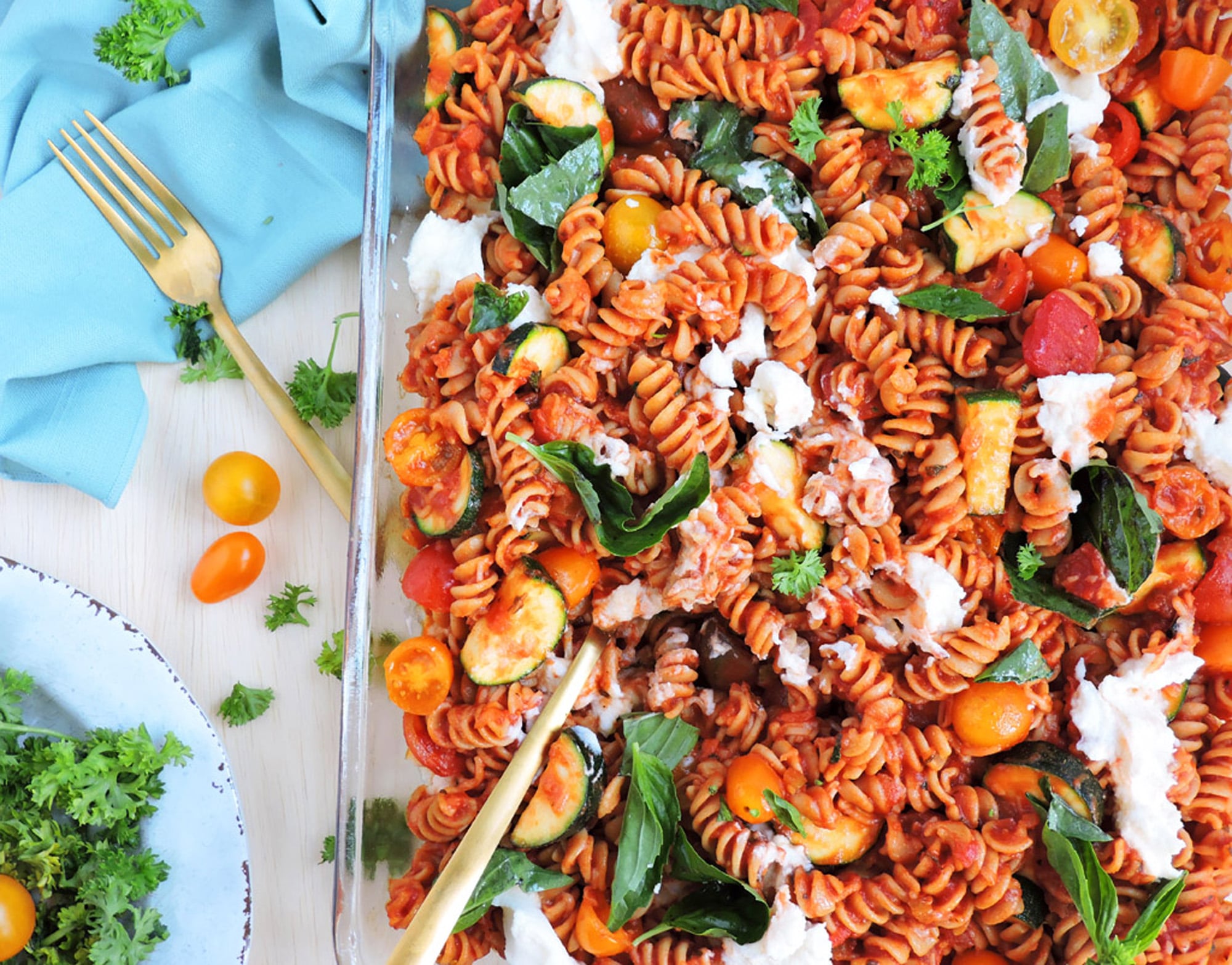 Veggie-Loaded Whole Wheat Pasta Bake in a glass casserole dish with basil leaves, ricotta and tomatoes on top
