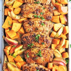 Sheet Pan Honey Glazed Pork Chops with Sweet Potatoes & Apples on a baking sheet pan with green parsley on top