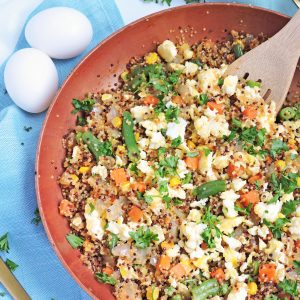 Easy Vegetable Fried Quinoa with scrambled eggs, green peas, carrots in a white bowl