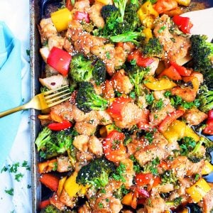 Sheet-Pan Teriyaki Ginger Sesame Chicken & Broccoli with yellow and red bell peppers, broccoli, and chicken on a sheet pan