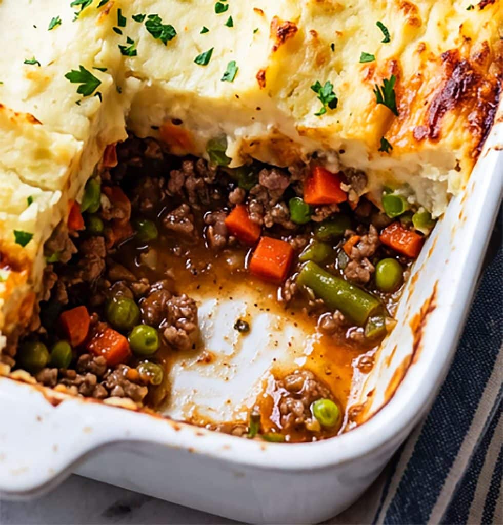shepherd's pie in a white casserole dish topped with fresh chopped parsley
beautifuleatsandthings.com