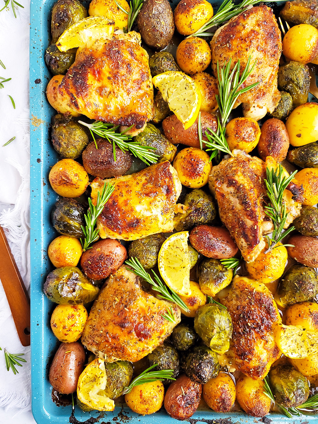 This Lemony Rosemary Sheet Pan Chicken with Brussels Sprouts & Potatoes the perfect weeknight meal; made on a blue sheet pan with chicken thighs, roasted potatoes, Brussels sprouts, lemon wedges and rosemary. beautifuleatsandthings.com