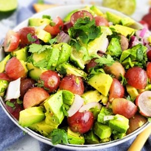 Grape and avocado salsa made with red California grapes, red onions, avocado, lime and cilantro in a white bowl. beautifuleatsandthings.com
