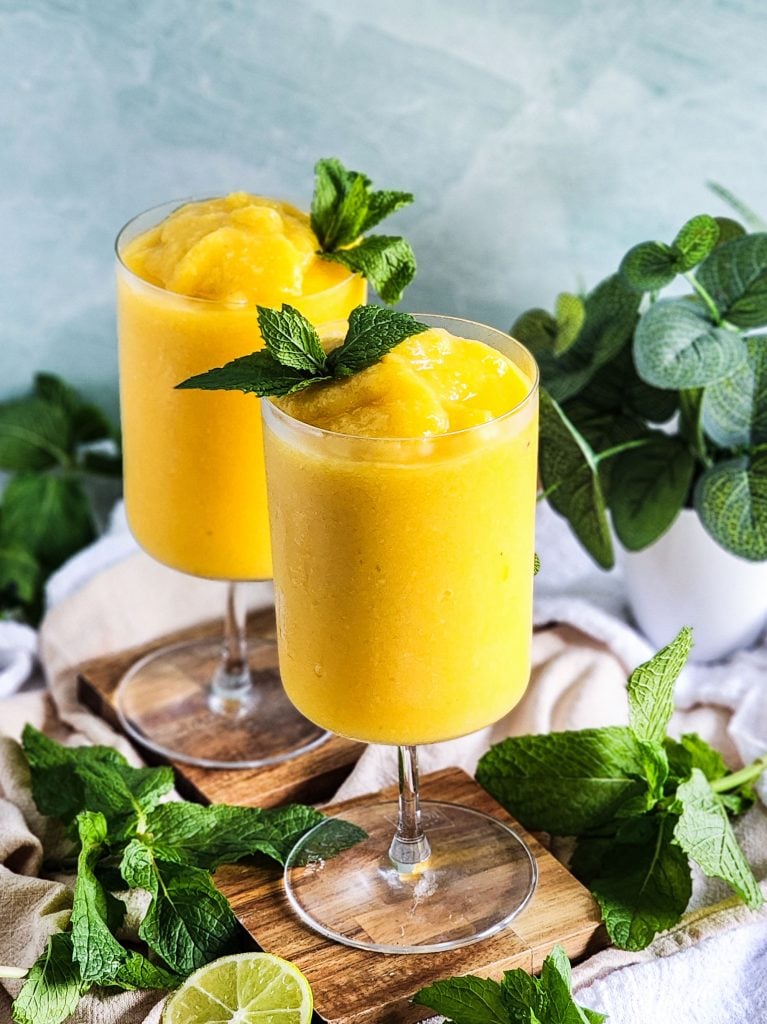 Passionfruit Mango Pineapple Frosé in a cocktail glass topped with fresh mint beautifuleatsandthings.com