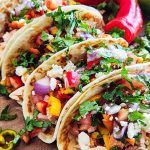 salmon tacos with a sweet pepper salsa topped with feta and cilantro on a wooden cutting board beautifuleatsandthings.com