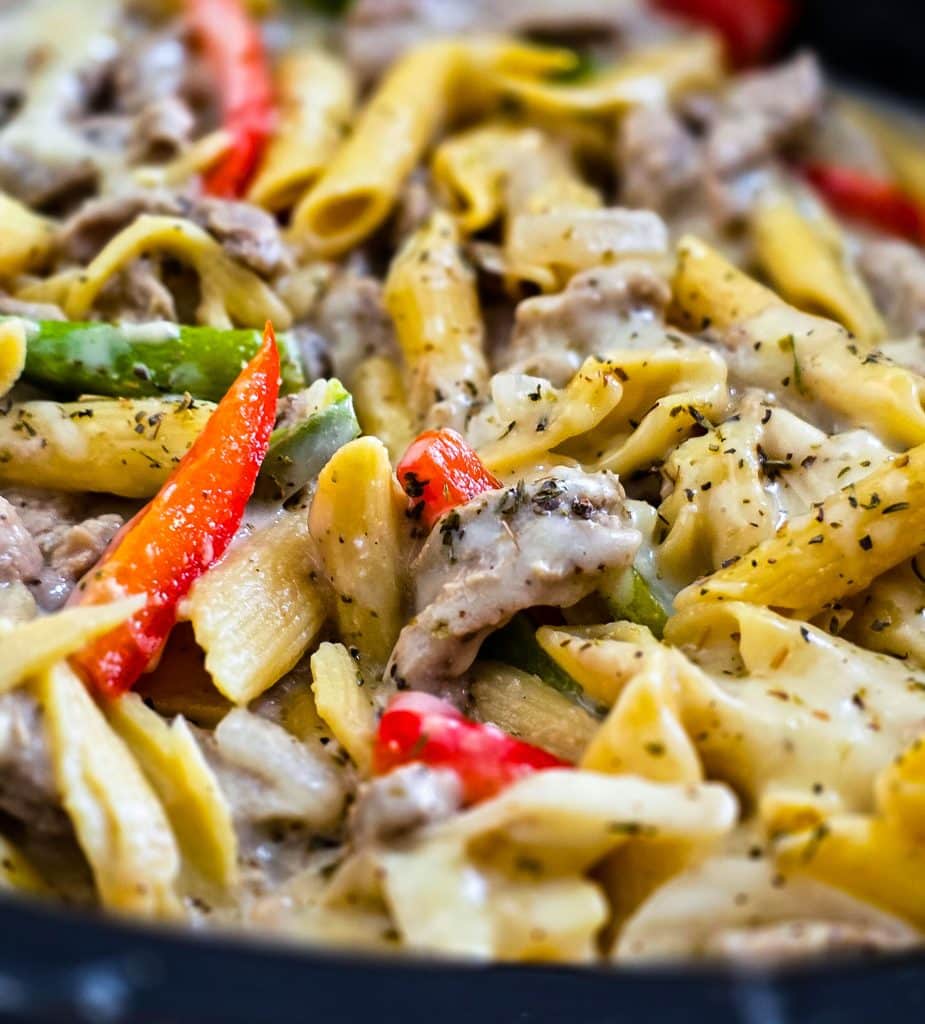 Easy Crockpot Philly Cheesesteak Pasta made in a black slow cooker with red and green bell peppers beautifuleatsandthings.com