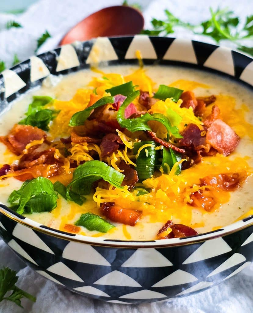 Loaded Potato Crockpot Soup, made in a slow cooker, budget-friendly served in a black and white soup bowl topped with shredded cheese, bacon, and green onions
beautifuleatsandthings.com