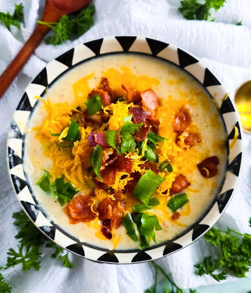 Loaded Potato Crockpot Soup, made in a slow cooker, budget-friendly served in a black and white soup bowl topped with shredded cheese, bacon, and green onions
beautifuleatsandthings.com