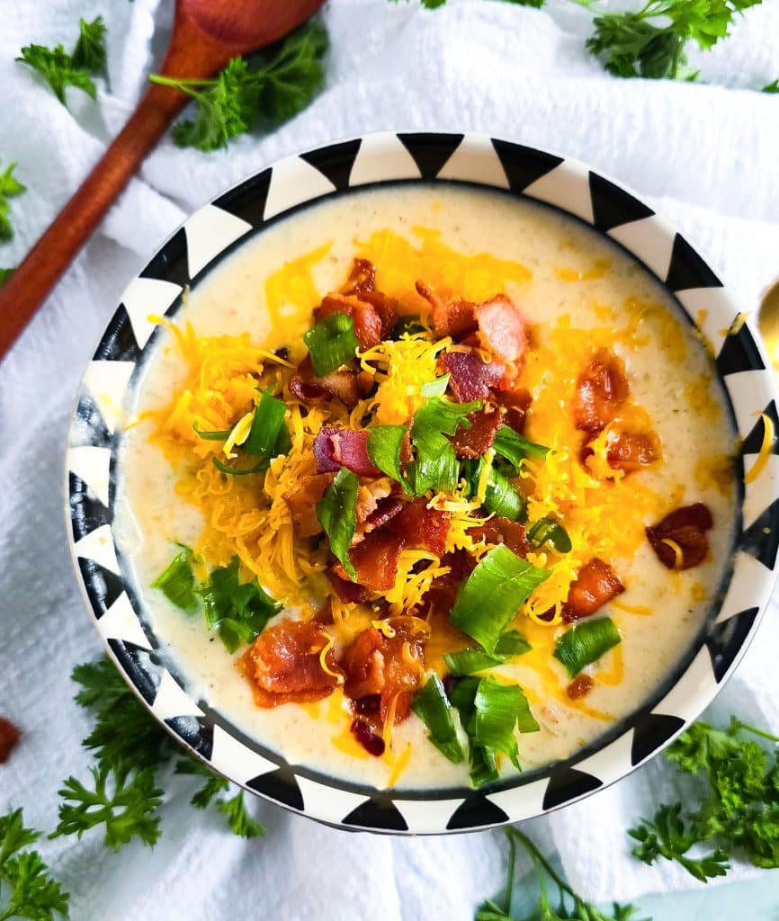 Loaded Potato Crockpot Soup, made in a slow cooker, budget-friendly served in a black and white soup bowl topped with shredded cheese, bacon, and green onions
beautifuleatsandthings.com
