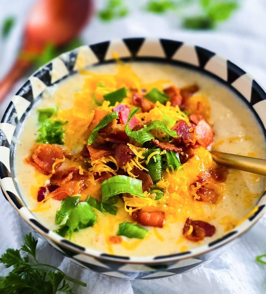 Loaded Potato Crockpot Soup, made in a slow cooker, budget-friendly served in a black and white soup bowl topped with shredded cheese, bacon, and green onions
beautifuleatsandthings.com
