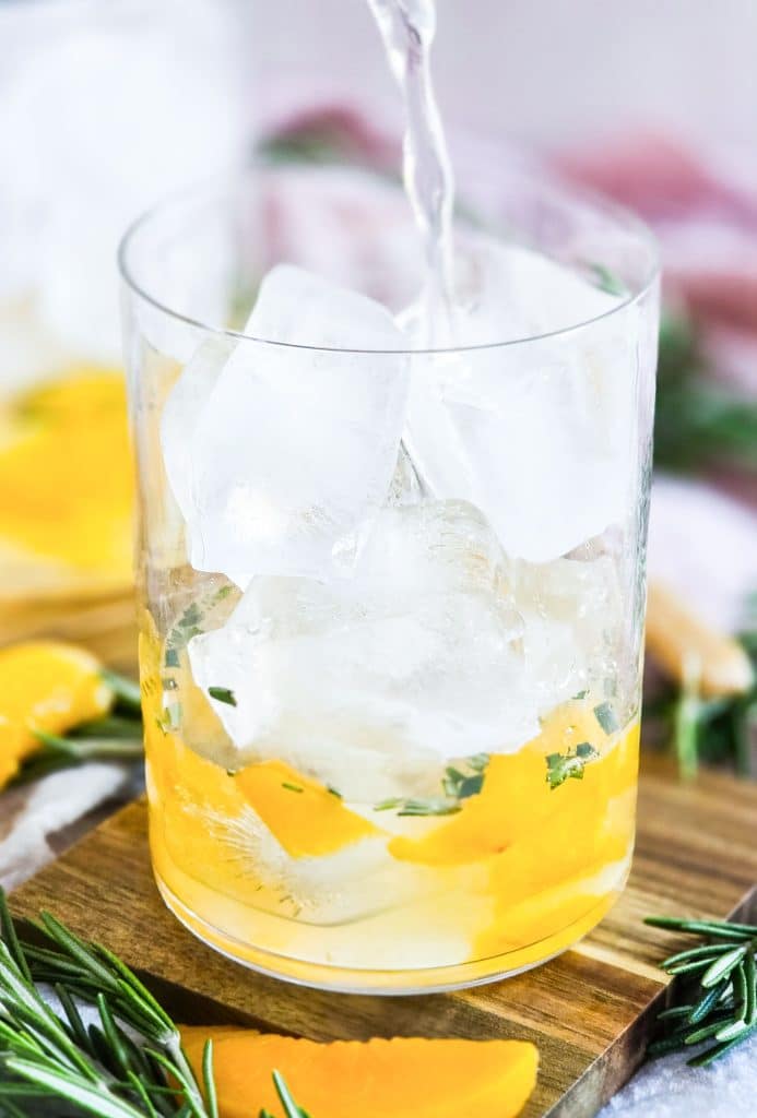ginger peach sparkling mocktail in a short cocktail glass, garnished with rosemary beautifuleatsandthings.com