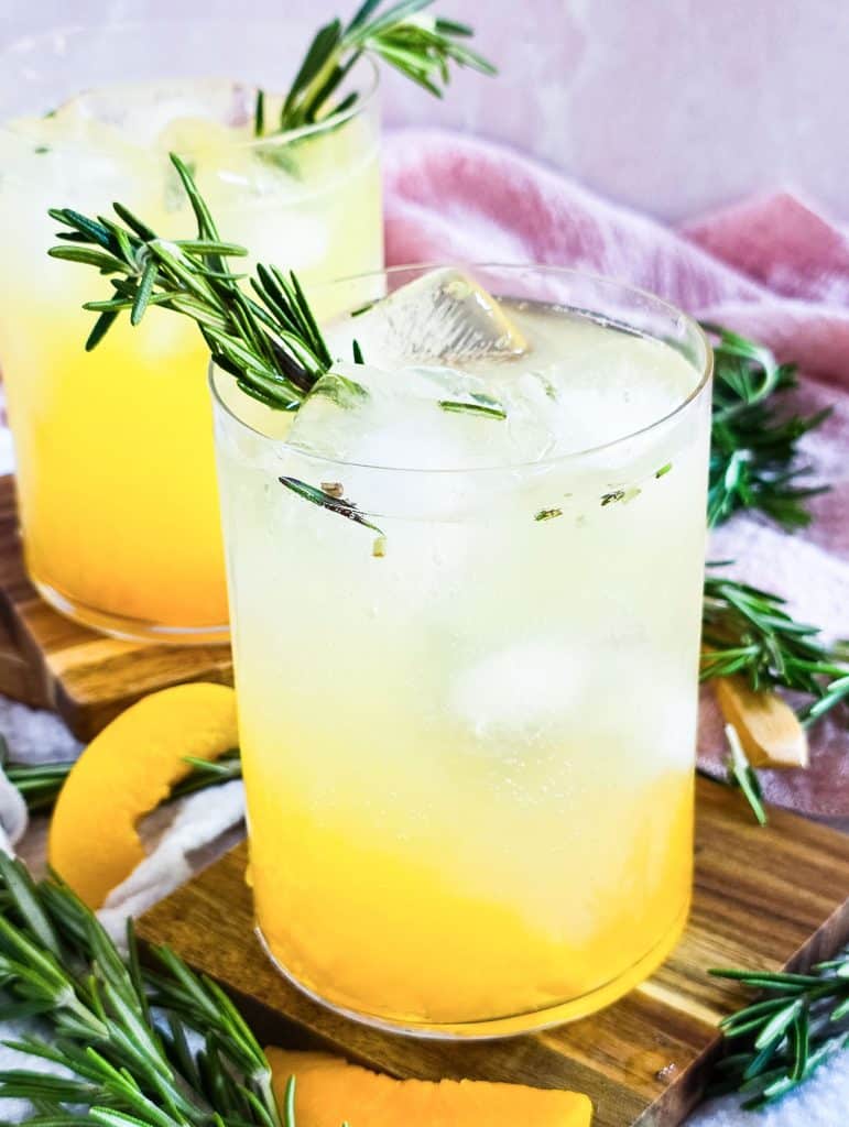 ginger peach sparkling mocktail in a short cocktail glass, garnished with rosemary beautifuleatsandthings.com