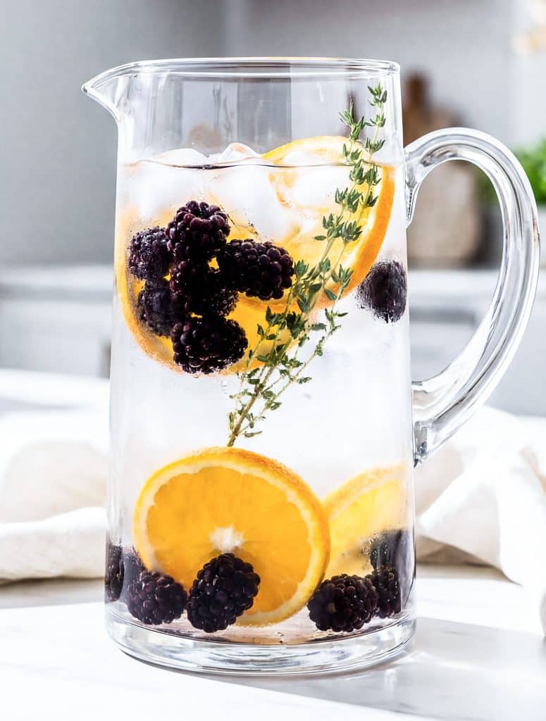 blackberry orange thyme infused water in a glass pitcher for hydration
beautifuleatsandthings.com