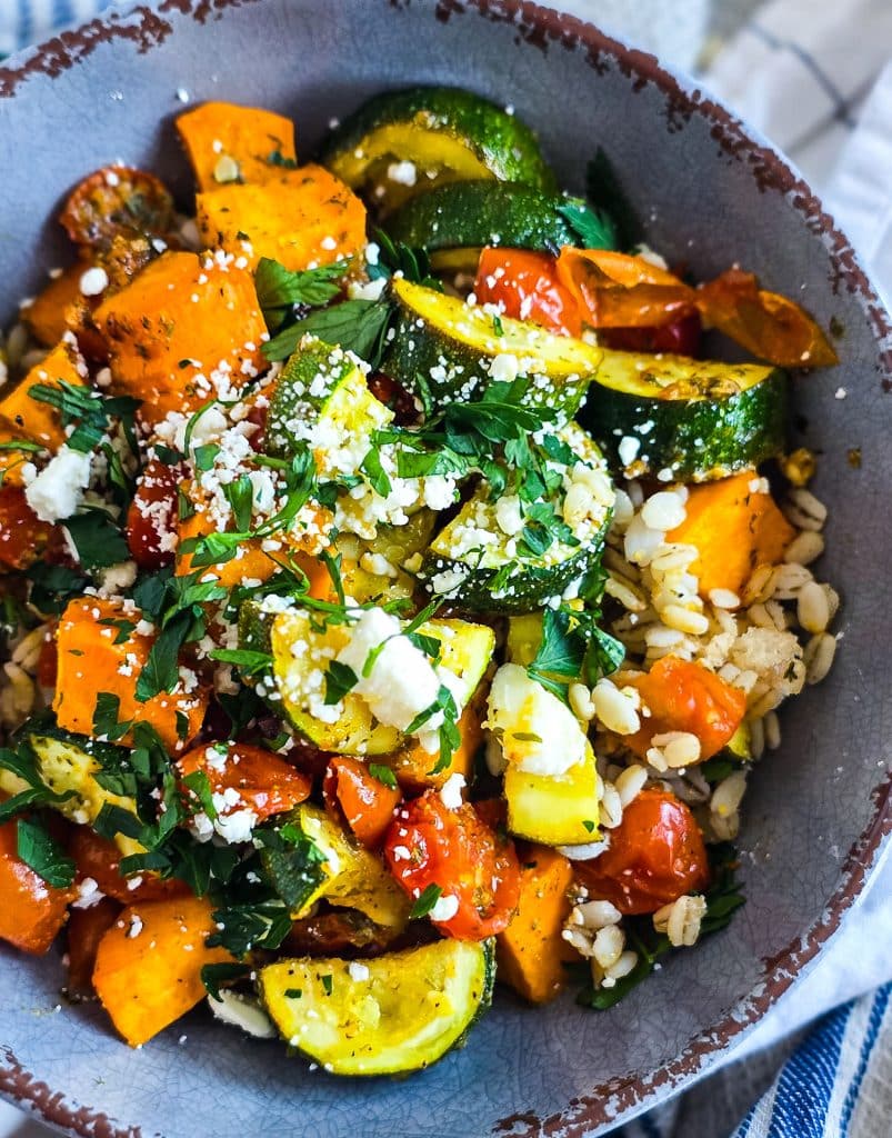 healthy high fiber grain bowl with zucchini, sweet potatoes, and tomatoes served over cooked barley in a gray bowl
beautifuleatsandthings.com