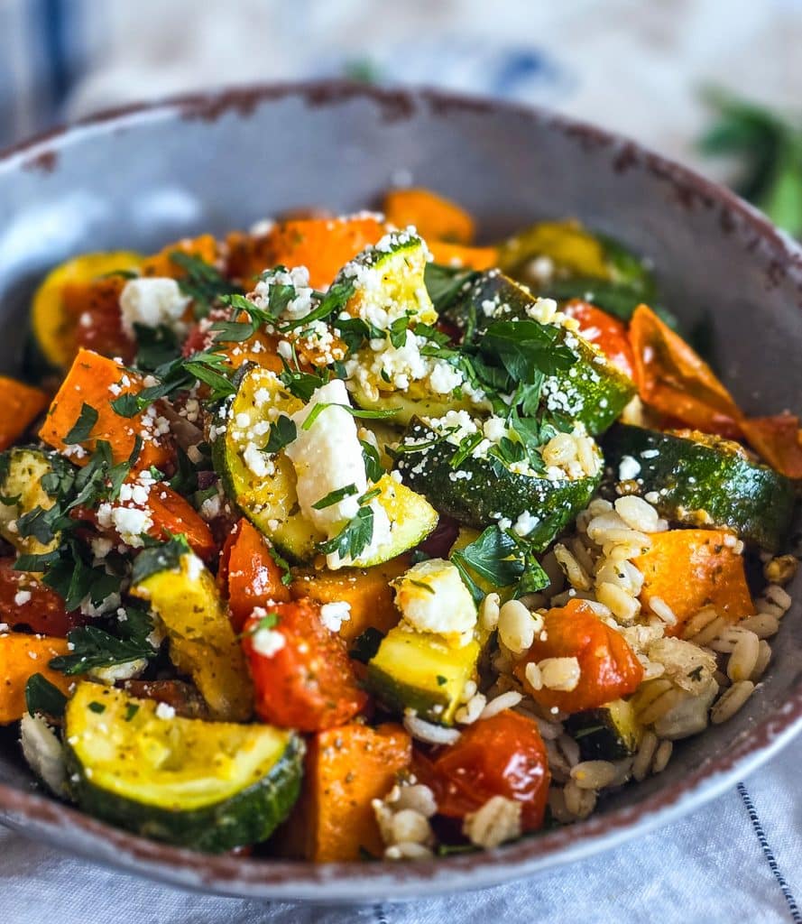healthy high fiber grain bowl with zucchini, sweet potatoes, and tomatoes served over cooked barley in a gray bowl
beautifuleatsandthings.com