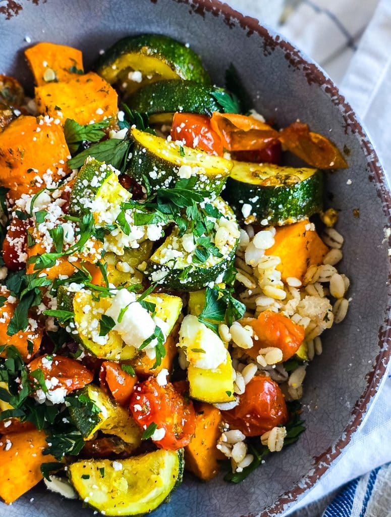 healthy high fiber grain bowl with zucchini, sweet potatoes, and tomatoes served over cooked barley in a gray bowl
beautifuleatsandthings.com