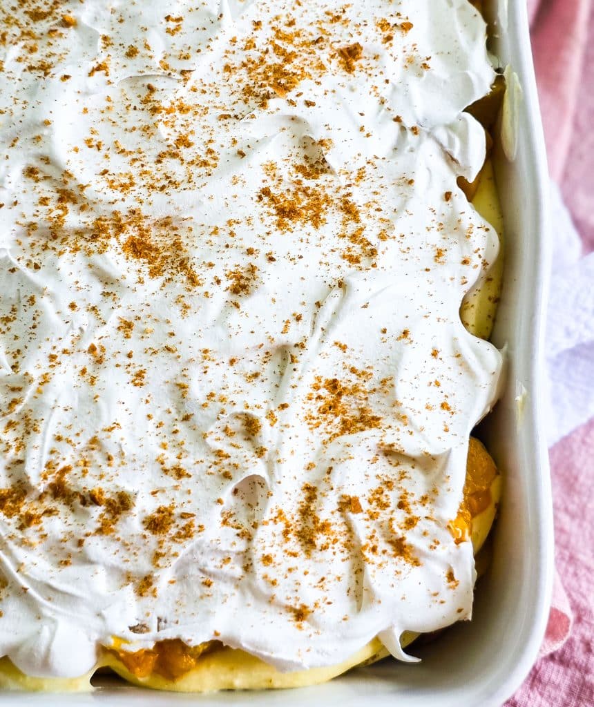 Easy no-bake peach pudding made with canned peaches, whipped topping, and vanilla wafers layered in a glass dish, served on a blue plate beautifuleatsandthings.com