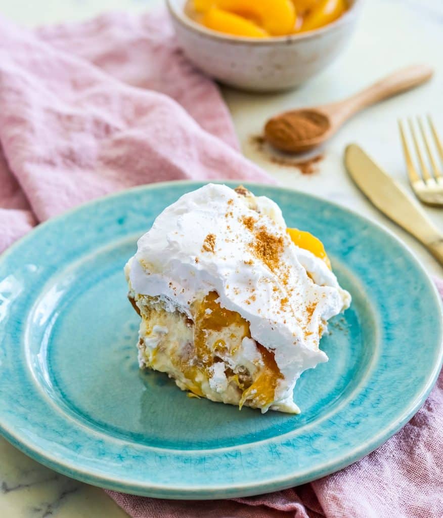 Easy no-bake peach pudding made with canned peaches, whipped topping, and vanilla wafers layered in a glass dish, served on a blue plate beautifuleatsandthings.com