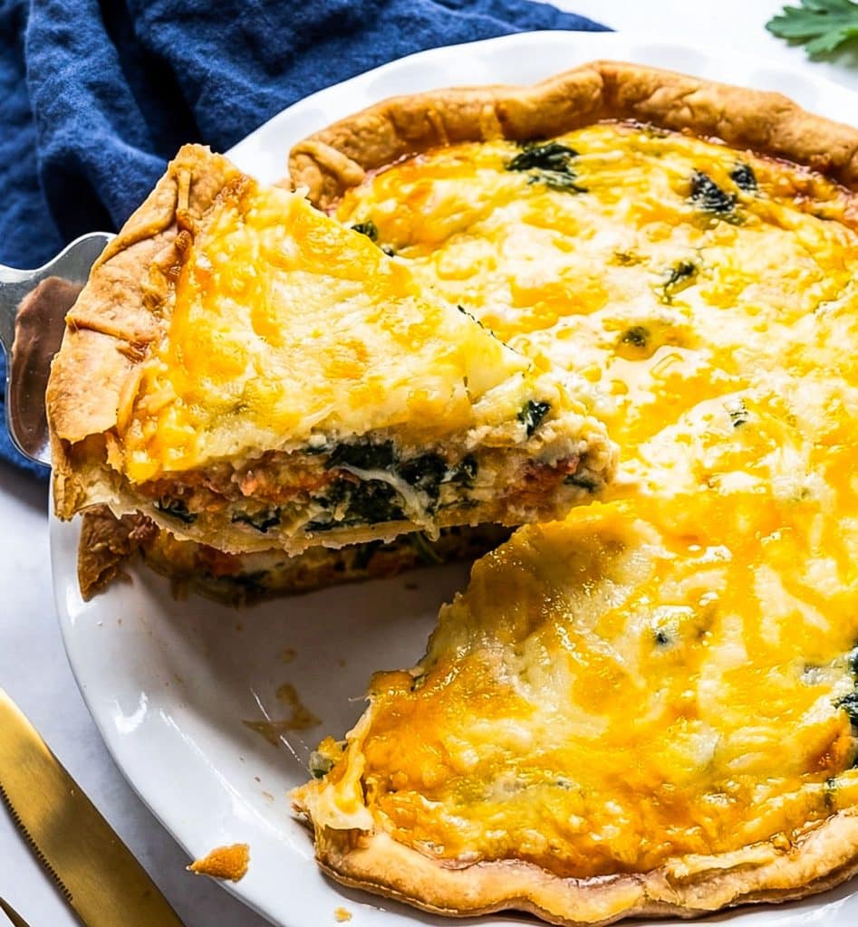 Golden baked salmon and spinach quiche made with sockeye salmon, spinach, cheddar, and Parmesan cheese in a flaky pie crust.