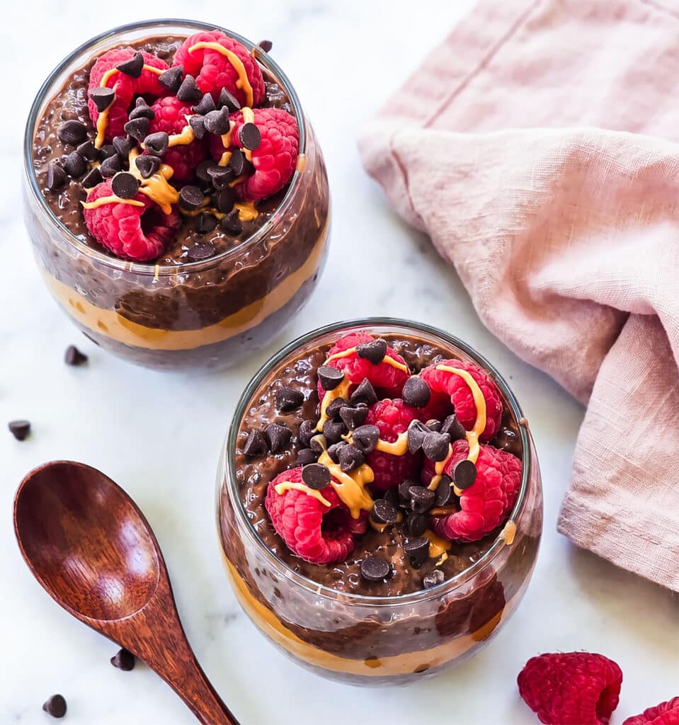 High-protein chocolate peanut butter chia pudding layered with peanut butter and topped with raspberries, chocolate chips and peanut butter drizzle.
