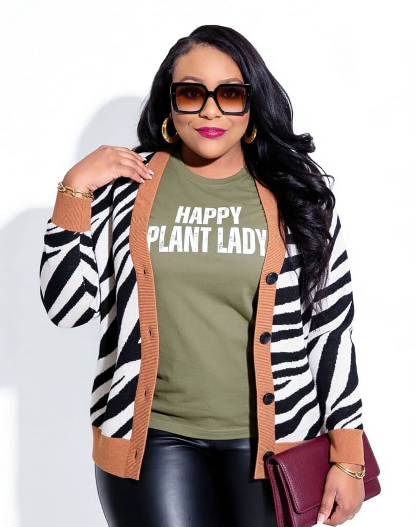 Plus size fall outfit with zebra print cardigan, olive graphic tee and black faux leather pants
